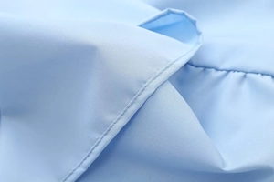 Close-up of light blue fabric texture with fine stitching and smooth ribbed finish