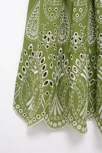 Detailed macro view of olive green midi dress with white eyelet floral embroidery and wavy hem