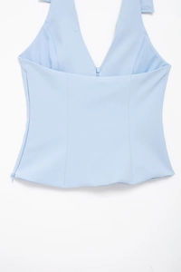 Detail of light blue halter neck top featuring structural waist seams and side zipper