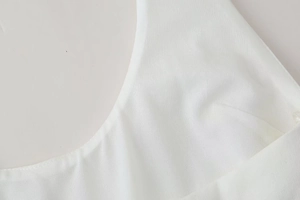 Detailed close-up of fine stitching and breathable fabric texture on a white summer dress