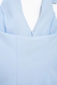 Detail of light blue V-neck top showing a seamless front zipper and woven texture