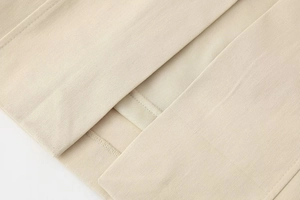 Macro detail of the beige midi dress showing premium twill texture and precision stitching