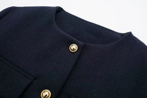 Detailaufnahme der dunkelblauen Strickjacke mit texturierten goldenen Metallknöpfen