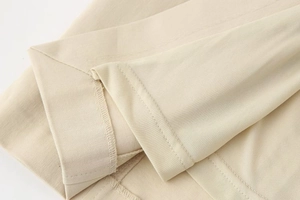 Close-up of twill fabric texture and reinforced double-stitched hem on a beige midi dress