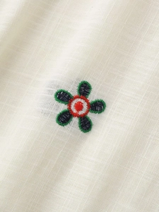 Vue macro d'une broderie florale sur chemise en lin beige avec texture de tissu détaillée