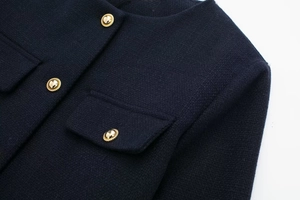 Detail der dunkelblauen Tweed-Jacke mit strukturierter Webart und goldenen Knöpfen