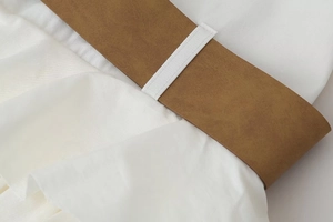 Detailed macro view of white chiffon dress fabric with brown leather belt and belt loops