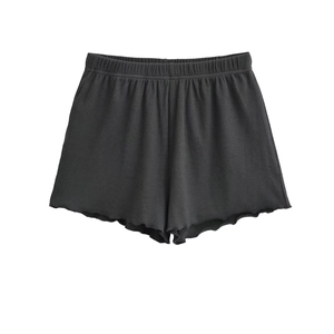 Detail of dark grey knit shorts featuring elastic waistband and wavy lettuce edge hem