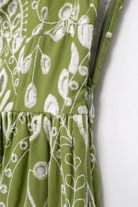 Detail of green Broderie Anglaise fabric with white embroidery and hidden side zipper