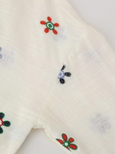 Gros plan détaillé de broderies florales colorées sur un tissu en lin blanc respirant