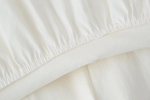 Macro view of white pleated fabric with precise elastic stitching and fine twill texture