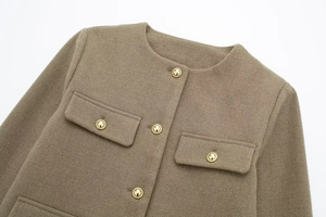 Detail der Tweed-Jacke mit goldenen Reliefknöpfen und symmetrischen Pattentaschen
