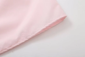 Close-up of fine stitching and hem detail on light pink fabric of the slim tube top
