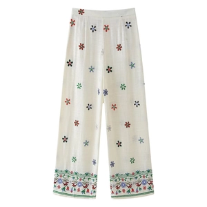 Détail de broderie florale sur pantalon large blanc cassé au style bohème élégant