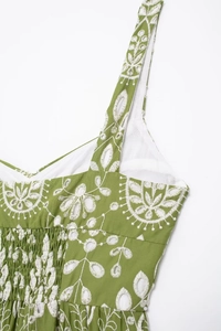 Detail of green midi dress featuring white floral embroidery and elastic pleated bodice