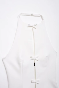 Detailansicht eines weißen Halterneck-Tops mit elegantem Frontschlitz und kleinen Schleifen