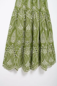 Detail of green summer dress featuring white floral eyelet embroidery and scalloped edges
