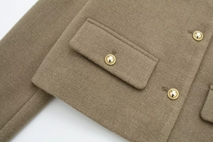 Detailaufnahme einer braunen kurzen Jacke mit goldenen Knöpfen und Taschenklappen