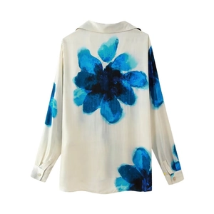 Detail of a white long-sleeve shirt featuring blue floral prints and buttoned cuffs