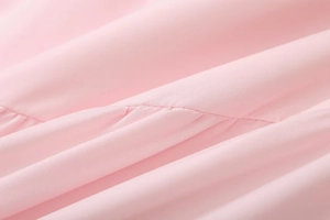 Macro detail of pink fabric showing fine stitching and soft pleated texture of the crop top