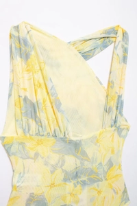 Detail of yellow floral mesh fabric with asymmetric pleats and crossover halter neckline
