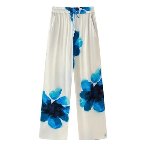 Detail of white wide-leg trousers featuring blue floral print and elastic drawstring waist