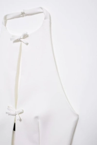 Detailansicht des weißen Neckholder-Tops mit eleganten Schleifen und Metallverschluss
