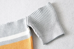 Detail of ribbed knit fabric on a cropped off-shoulder top with grey white and orange stripes