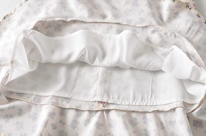 Détail du tissu en mousseline à fleurs mauves avec doublure blanche opaque de la robe