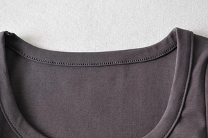 Detail of a dark gray knit top featuring a ribbed neckline and high-quality stitching
