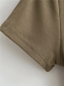 Macro shot of olive green ribbed knit fabric showing sleeve hem and dual stitching detail
