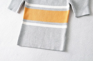 Detail shot of grey ribbed knit top showing yellow and white striped patterns