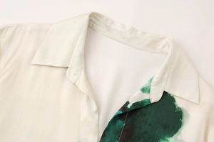 Detailed view of the silk-like shirt collar with elegant green artistic print patterns