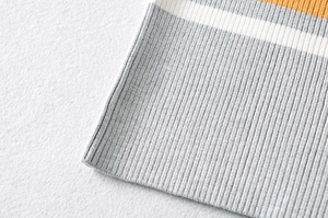 Close-up of ribbed knit cuff with gray, white, and orange stripes on crop top