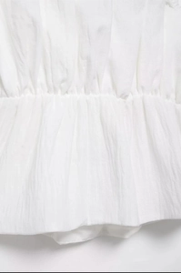 Detailed macro view of white smocked elastic waist fabric with fine cotton texture