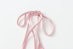 Detail of light pink satin dress showing premium cross-tie straps and smooth texture