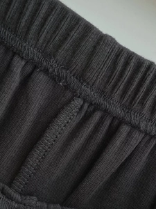 Detailed view of elastic waistband and overlock stitching on ribbed dark gray fabric