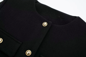 Nahaufnahme der schwarzen Tweedjacke mit goldenen Vintage-Knöpfen und elegantem Rundhals