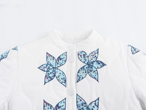 Detail of white quilted jacket with blue floral print and fabric-covered buttons