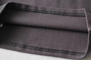 Detail shot of overlock stitching and knit fabric texture on a dark grey cropped top