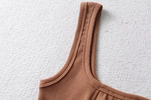 Close-up of brown ribbed knit fabric showing shoulder straps and precise stitching details