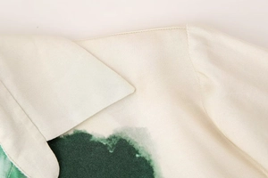 Detail view of champagne satin shirt collar with green abstract print and fine stitching