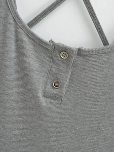 Détail d'une robe en maille grise avec patte de boutonnage et bretelles croisées