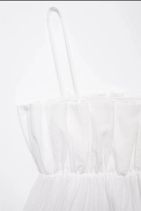 Detailed close-up of white summer camisole featuring ruffled neckline and thin straps
