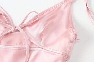 Detail of light pink satin dress showing delicate straps, V-neckline, and side zipper