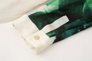 Close-up of cream white buttoned cuff on green abstract ink print long sleeve shirt