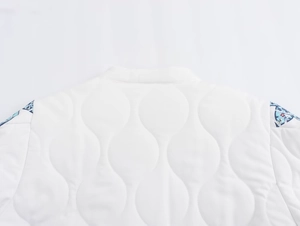 Detailed macro view of white quilted jacket with floral pattern stitching on shoulders