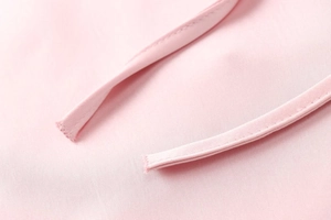 Close-up detail of light pink satin dress with elegant drawstring and twill texture