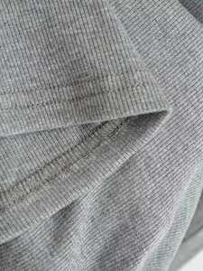 Gros plan sur le tissu gris à maille côtelée montrant les détails des doubles coutures