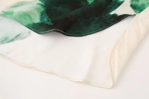 Detail of green watercolor printed satin fabric featuring fine stitching and white hem line